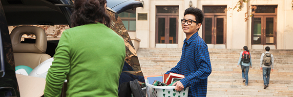 A college student unloads his car full of suitcases and school supplies as he moves into college.